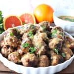 Turkey meatballs in a white dish with oranges and cilantro in the background