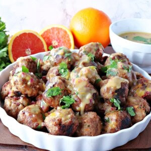 A white dish filled with Turkey Meatballs with Orange and Cashew topped with cilantro.