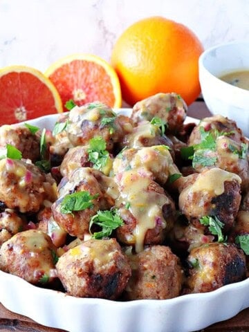 A white dish filled with Turkey Meatballs with Orange and Cashew topped with cilantro.