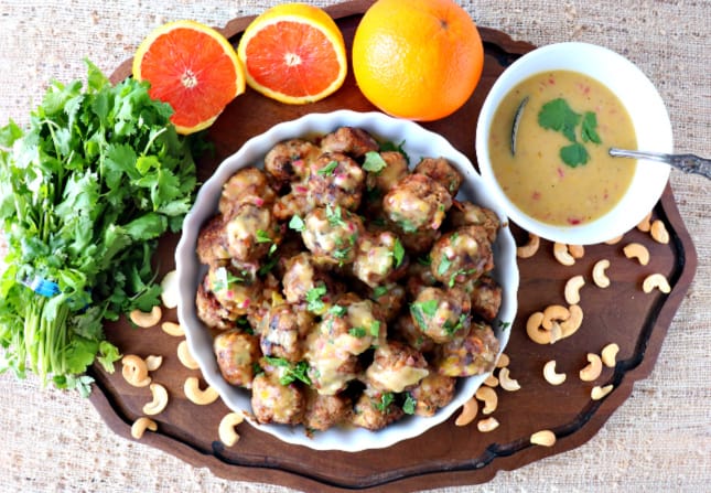 Overhead picture of a dish of turkey meatballs with sauce, cashews, oranges, and cilantro.