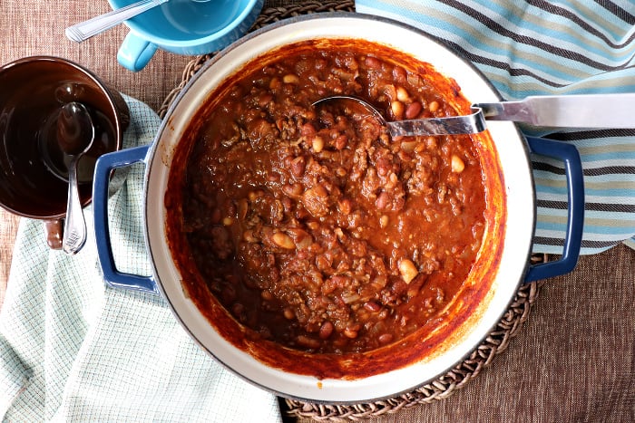 Overhead picture of a pot of spaghetti squash chili with a ladle and two soup mugs.