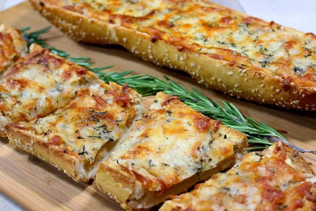 Two long loaves of roasted garlic cheese bread with sprigs of rosemary in the center.