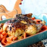 Whole chicken in a teal blue roaster with carrots