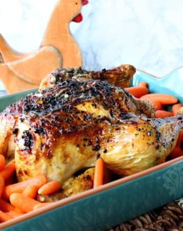 Whole chicken in a teal blue roaster with carrots
