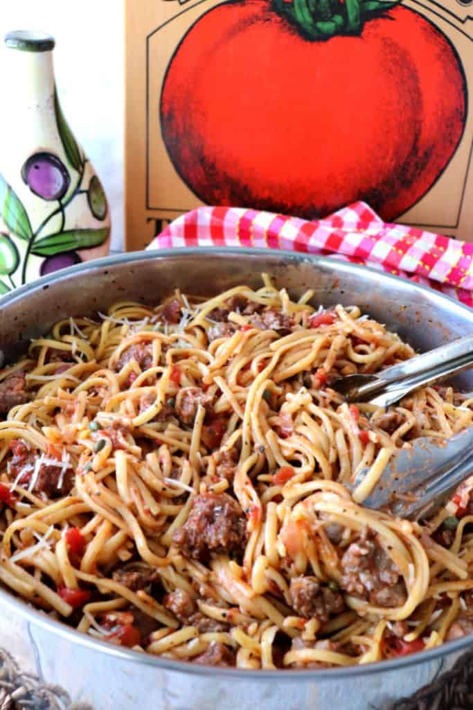 A large pot of linguine pasta with a tomato picture and an olive oil decanter in the background.