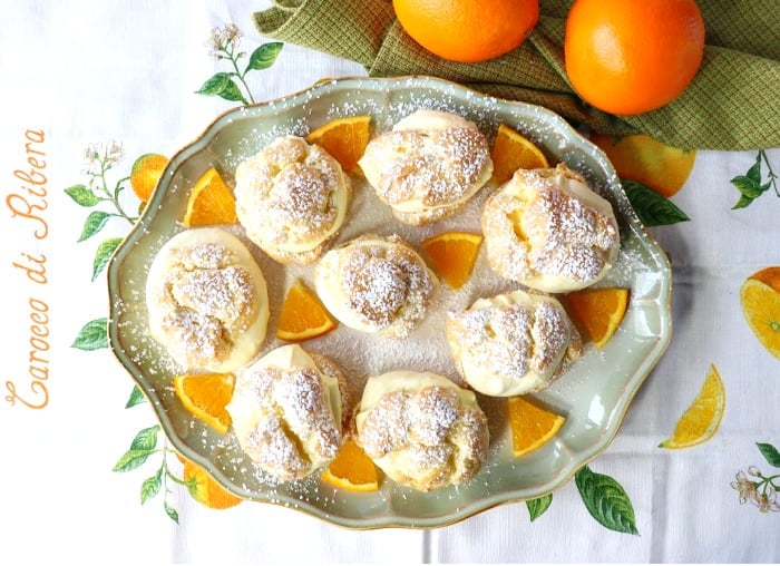 Overhead picture of a platter of eclairs with whipped cream and orange pieces