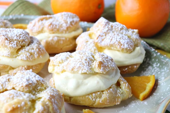 Perfect Profiteroles with Orange Curd Whipped Cream Filling Closeup picture of profiterole with orange cream filling and a confectioners sugar dusting