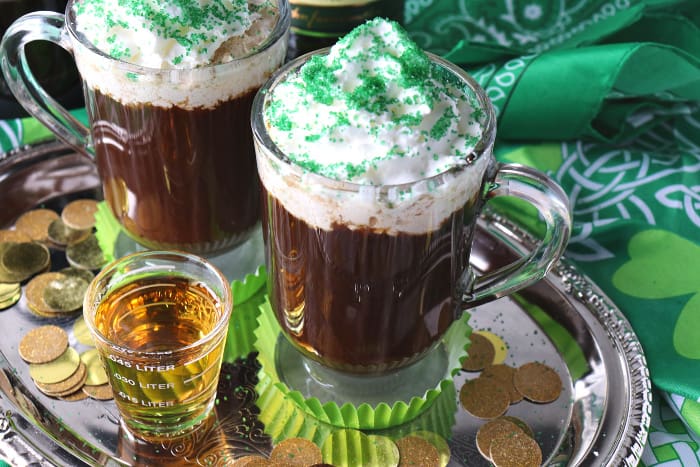 Shot of whiskey and a mug of Irish coffee on a sliver tray with whipped cream and green sugar