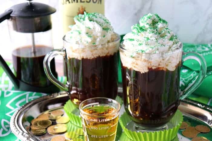 Two cups of Traditional Irish Coffee topped with whipped cream and green sugar.