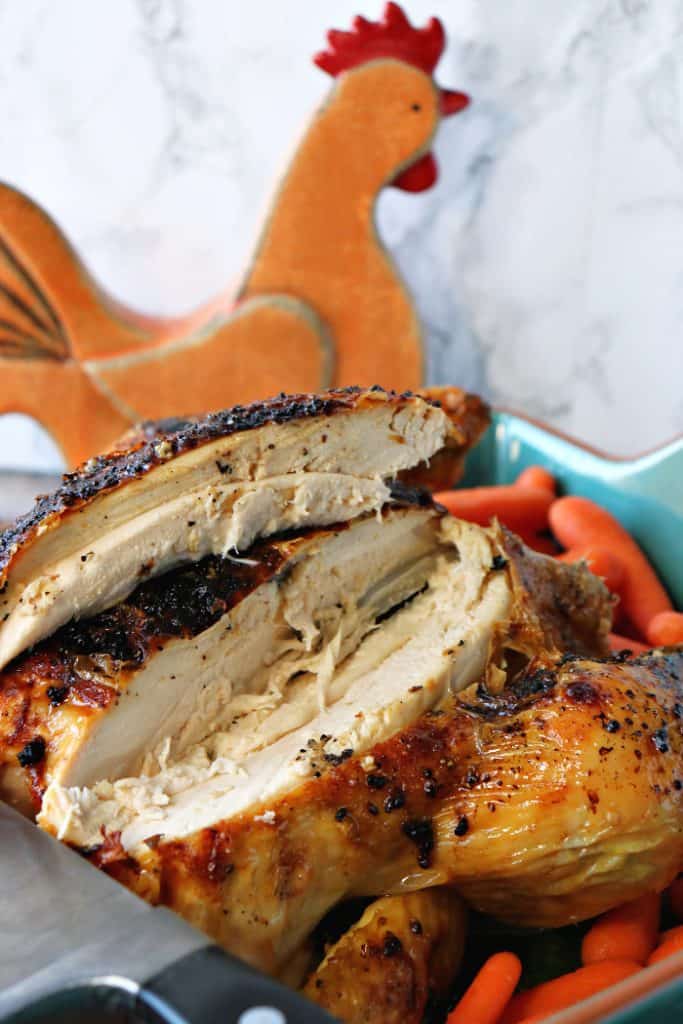 Sliced air fryer whole chicken with a ceramic chicken in the background
