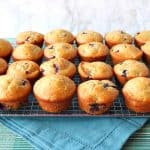 Cooling rack loaded with blueberry muffins and a blue napkin