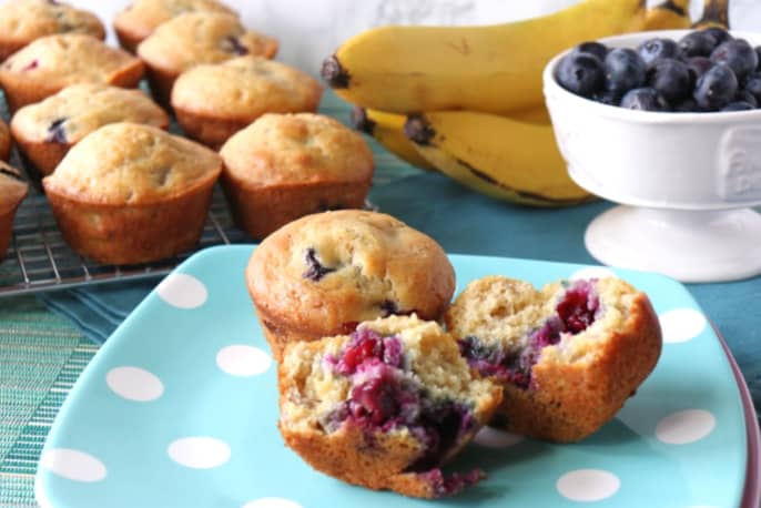 Two Blueberry Banana Muffins on a blue polka dot plate.