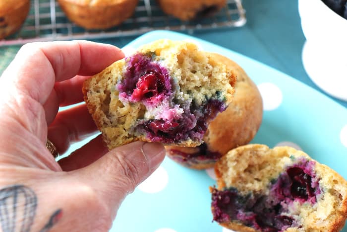 Hand holding a half of a blueberry banana muffin.