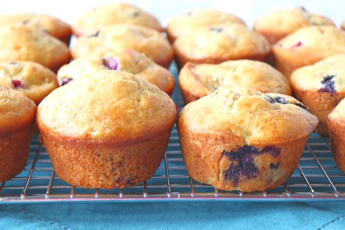 Closeup picture of rows of homemade muffins on a cooling rack with a blue napkin.