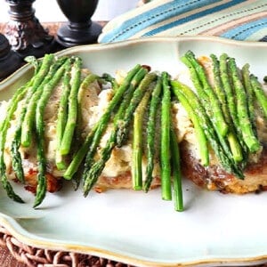 Three Breaded Chicken Oscar on a platter topped with asparagus.
