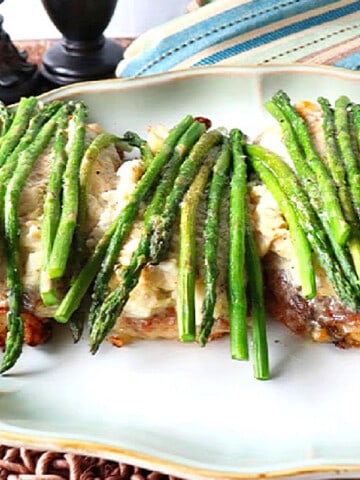 Three Breaded Chicken Oscar on a platter topped with asparagus.