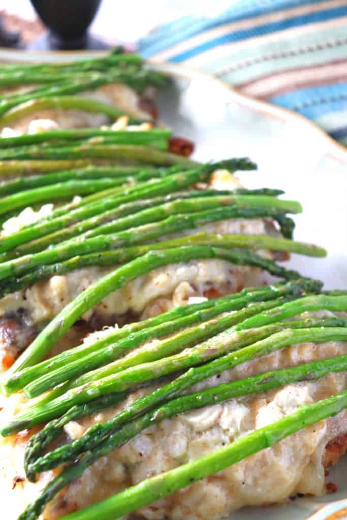 Vertical image of chicken Oscar with fresh asparagus spears over top