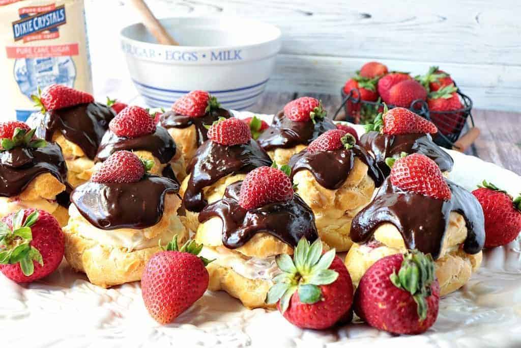 Plate of filled eclairs with chocolate ganache topping a strawberries