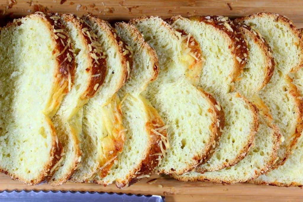 Italian Easter Cheese Bread Overhead shot of a loaf of bread sliced on a cutting board with a serrated knife
