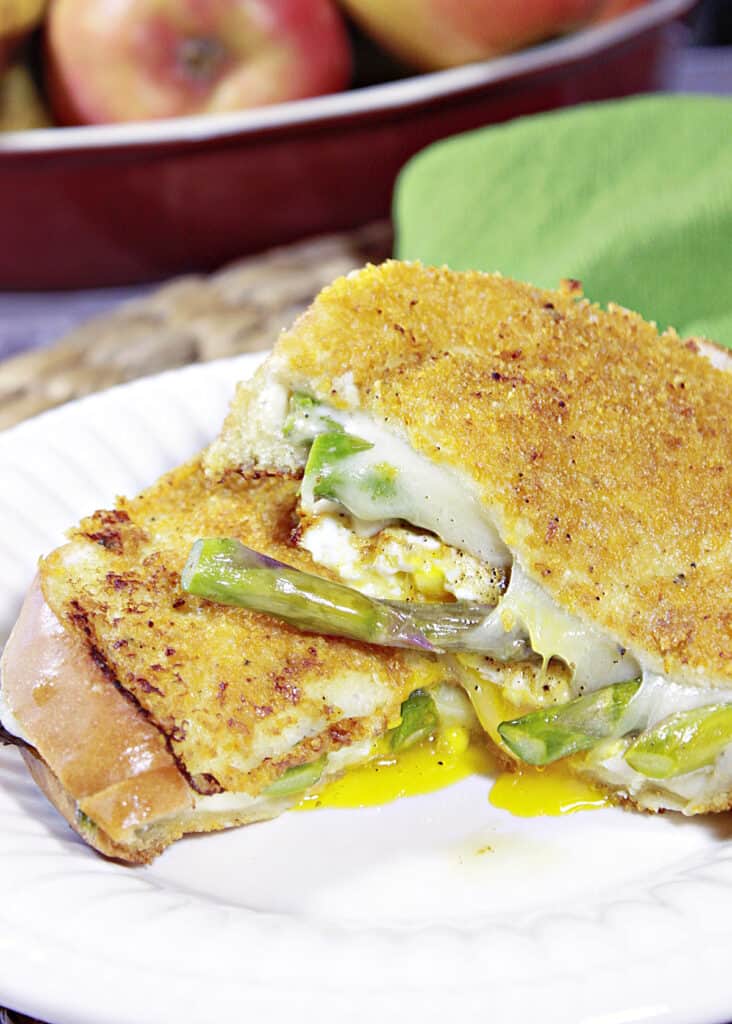 A vertical closeup of the inside of a Grilled Cheese Breakfast Sandwich with runny yolk, asparagus, and melted cheese.