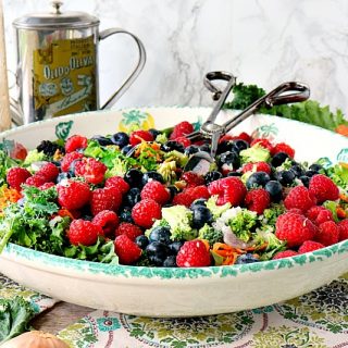 Large bowl with a kale salad with blueberries, raspberries, and blackberries.