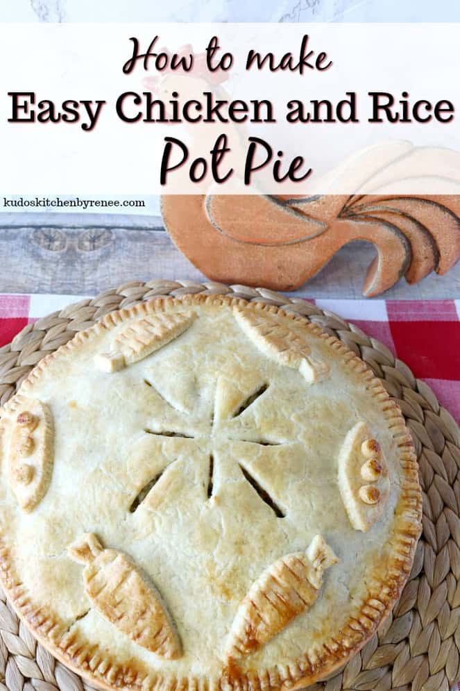 Overhead picture of a chicken pot pie with a decorated pie crust with carrots and peas.