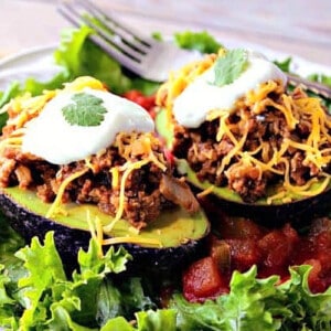 Two halves of a Turkey Taco Stuffed Avocado topped with cheese and sour cream.