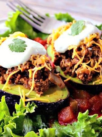 Two halves of a Turkey Taco Stuffed Avocado topped with cheese and sour cream.