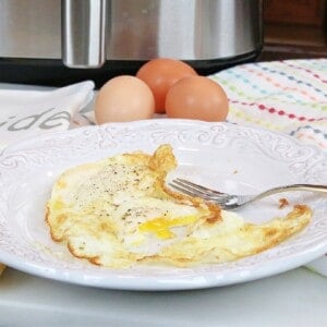 Two Air Fryer Fried Eggs on a white plate with eggs in the background.