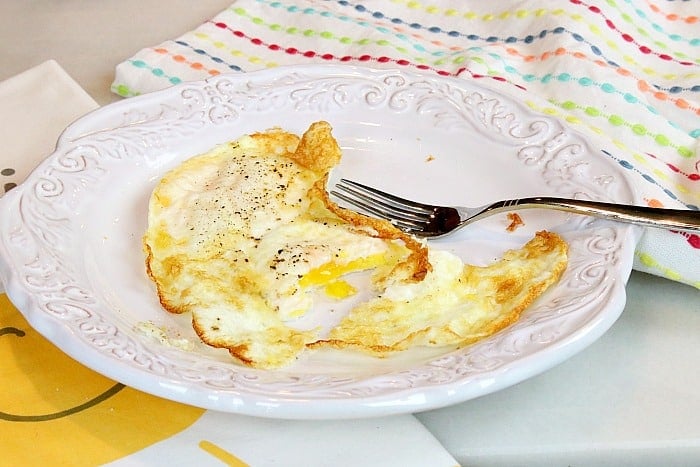 Air Fryer Fried Eggs on a white Plate with a fork.