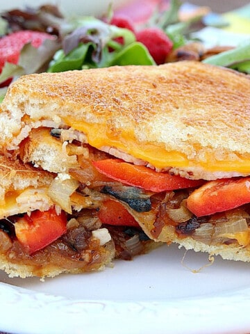 A grilled cheese sandwich with red pepper, cheese, and onions.