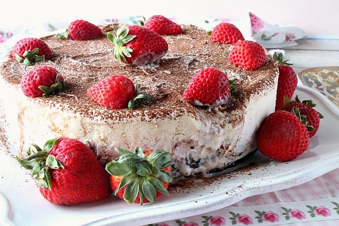 Melting Neapolitan ice cream cake with strawberries on a square white plate.