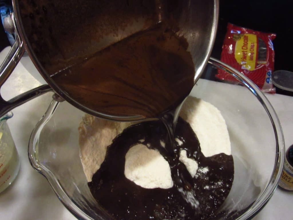 Liquid chocolate ingredients being added to dry ingredients to make a chocolate cherry Bundt cake.
