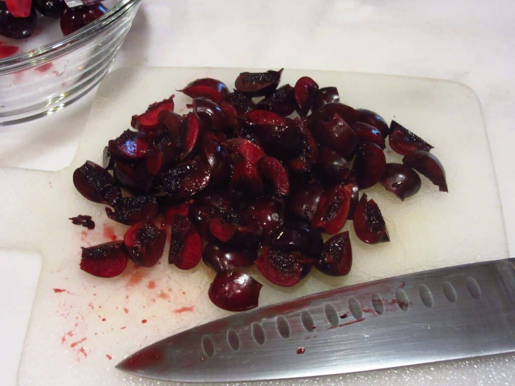 Chopped pitted cherries on a cutting board.