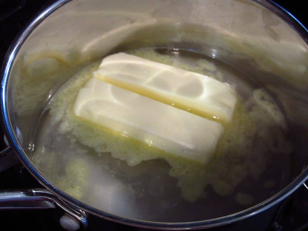 Two sticks of butter melting in a saucepan.
