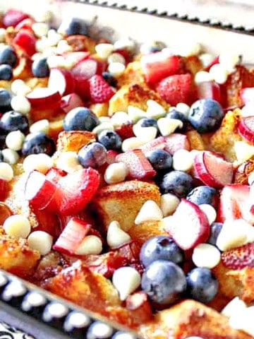 A casserole dish filled with Red, White, and Blue Bread Pudding with berries and white chocolate chips.