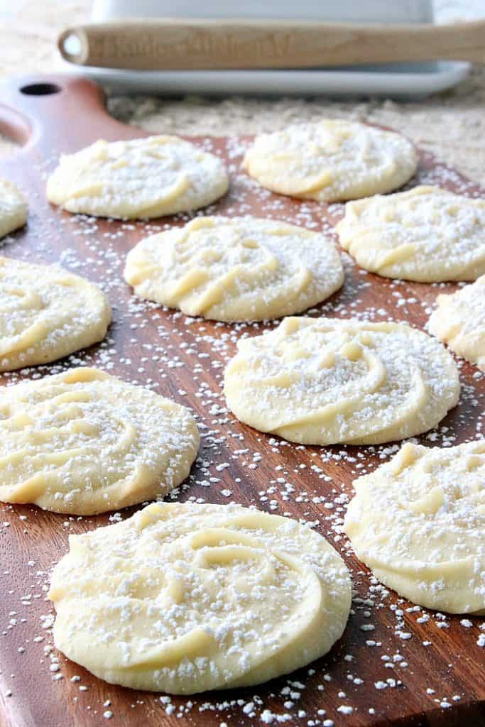 Closeup photo of delicate Viennese Whirls cookies on a wooden board with a confectioners sugar dusting.