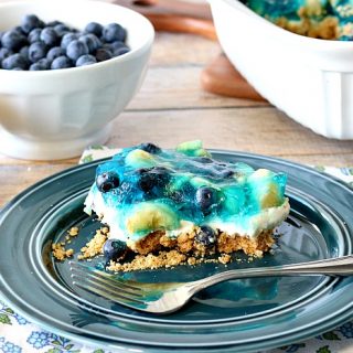 Slice of blueberry banana pretzel dessert on a blue plate with a fork.