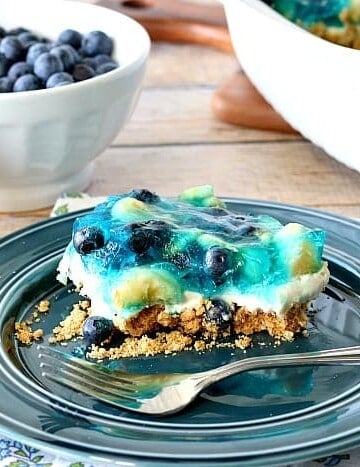 Slice of blueberry banana pretzel dessert on a blue plate with a fork.