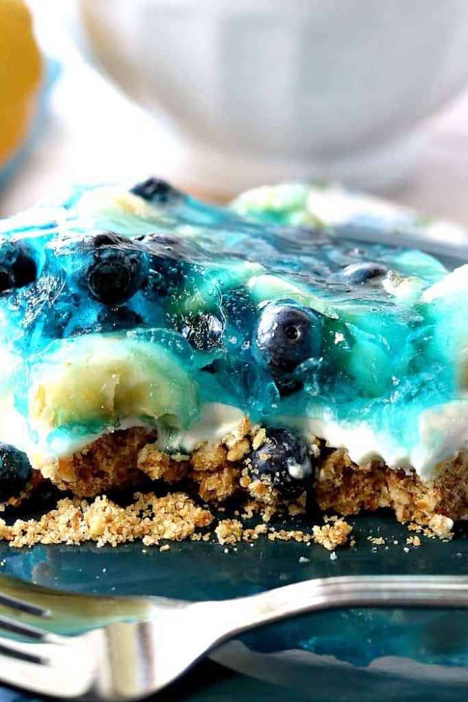 Closeup photo of a pretzel crusted blue gelatin dessert with bananas and blueberries.