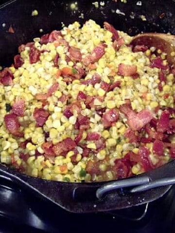 A cast iron pot filled with Fried Corn with Bacon.