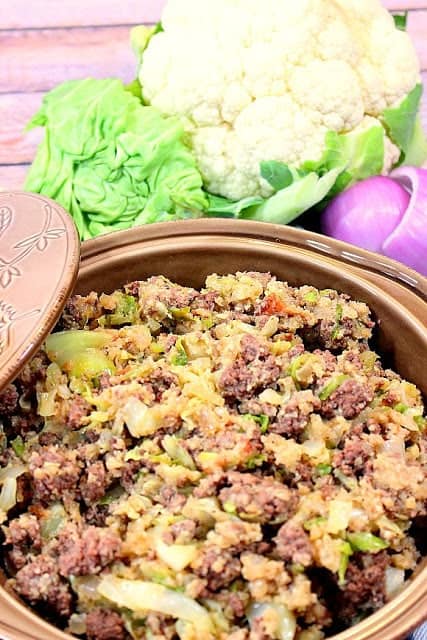 Casserole dish filled with keto cabbage roll casserole with cauliflower and cabbage in the background.