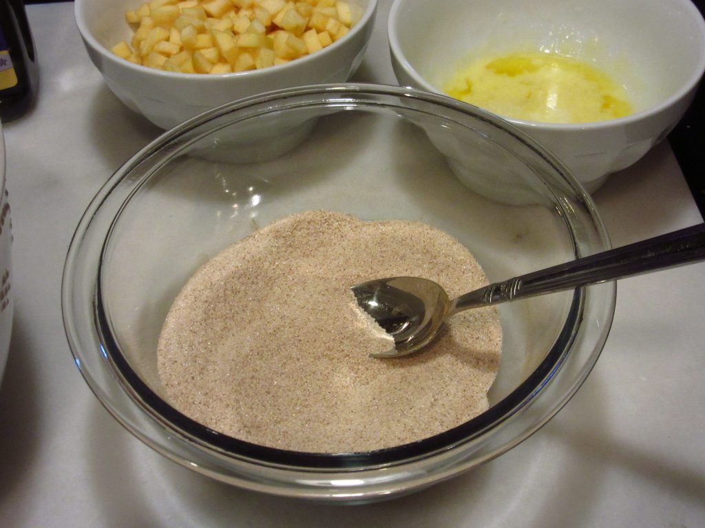 Cinnamon sugar in a glass bowl with a spoon.