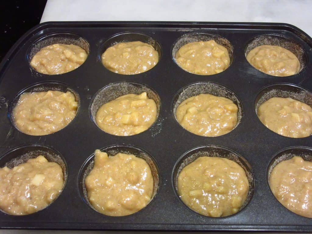 A muffin tin filled with donut muffins before baking.