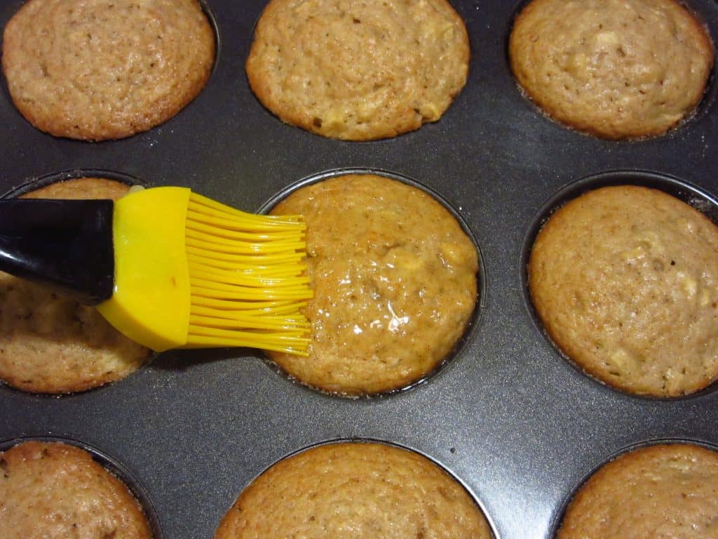 Melted butter being brushed over muffins.