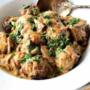 A bowlful of German Meatballs with Mushroom Caraway Sauce topped with parsley.