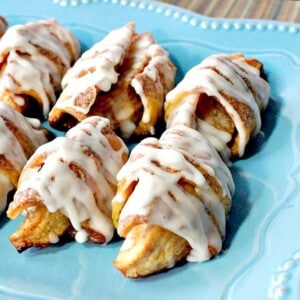 A blue plate holding a few glazed Apple Pie Wedges ready for eating.