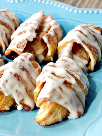 A blue plate holding a few glazed Apple Pie Wedges ready for eating.