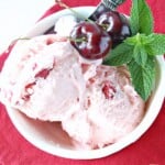 Scoops of No-Churn Cherry Chunk Amaretto Ice Cream in a bowl with cherries and mint.