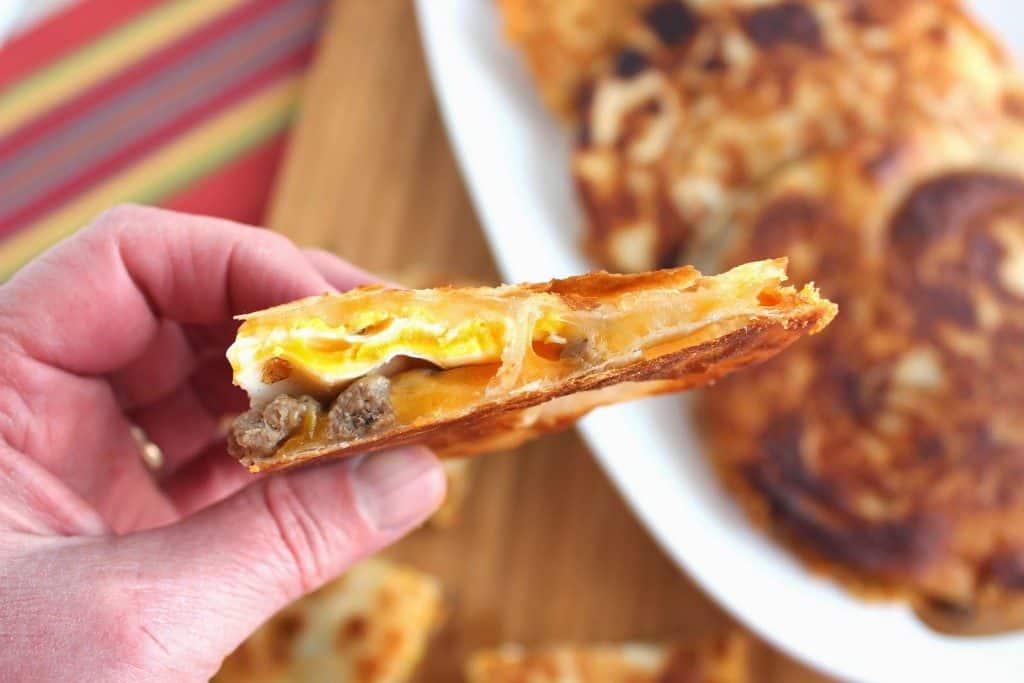 Closeup of the inside of a breakfast quesadilla with a fried egg, sausage, and cheese.